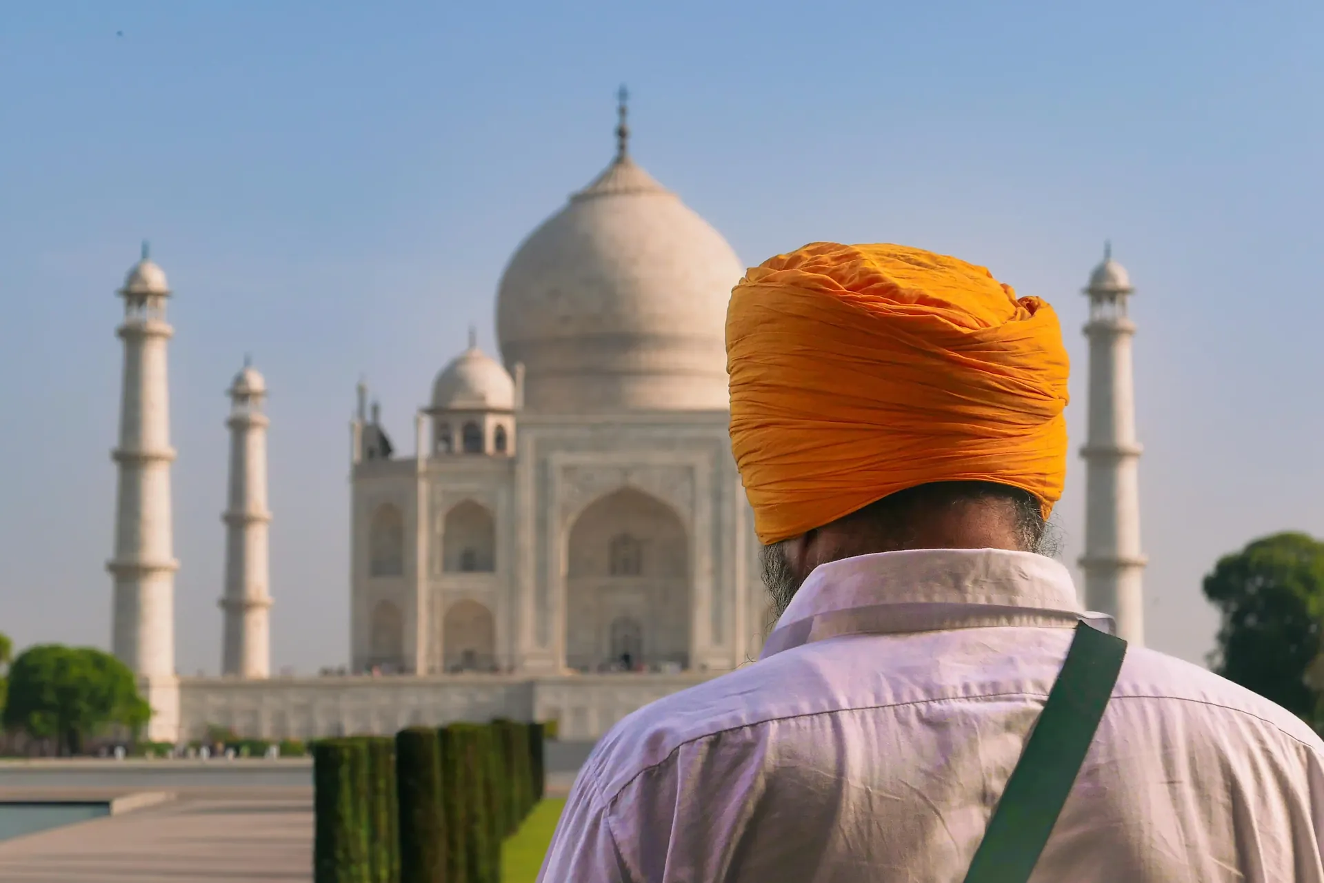 A visitor in an orange turban looking towards the Taj Mahal